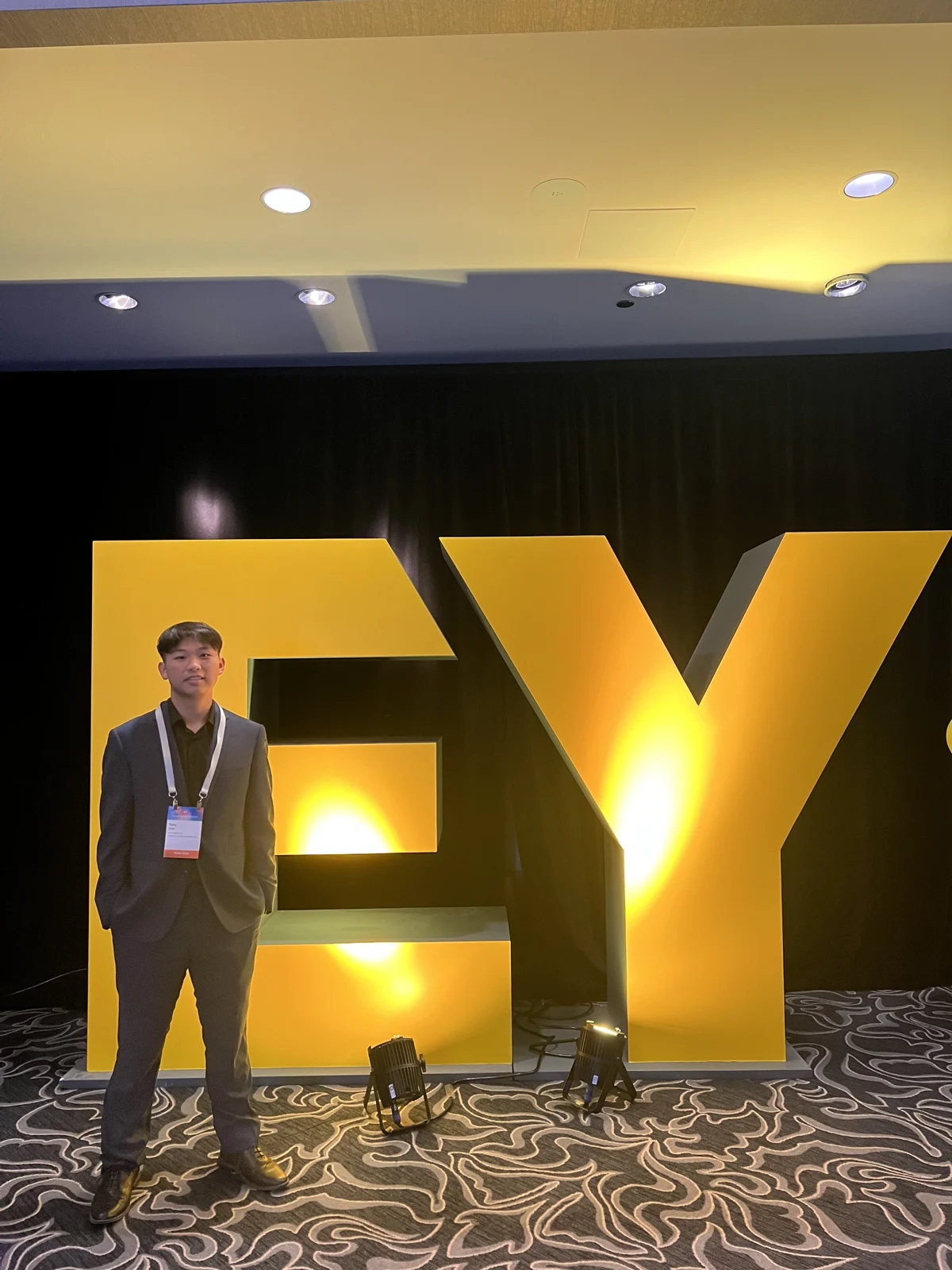 Tony standing beside a large EY sign at an event